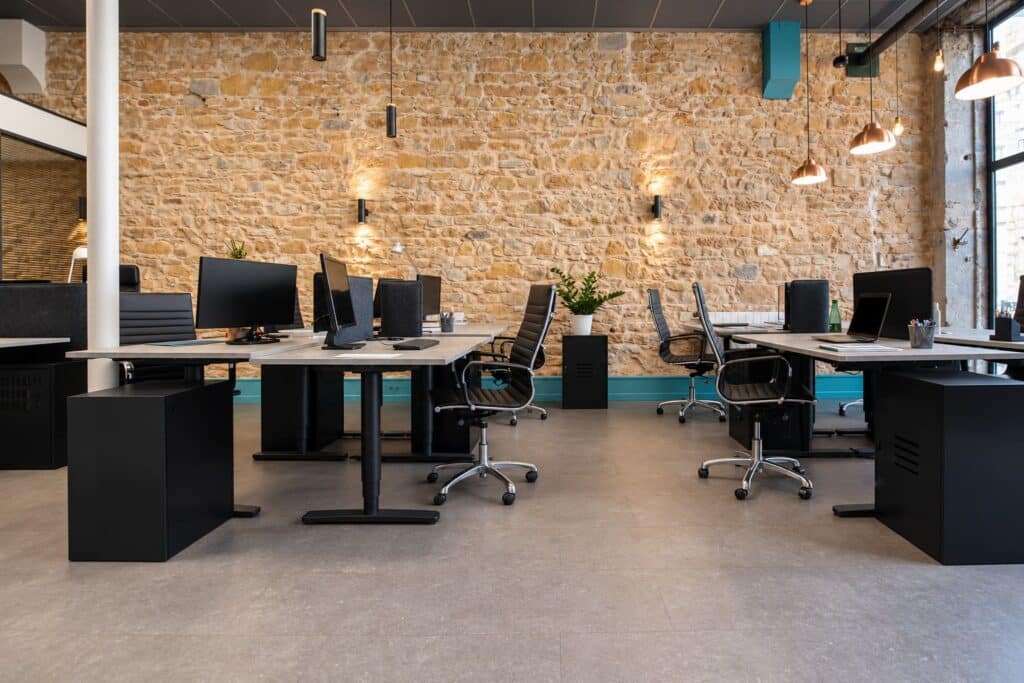 Postes de travail devant le mur en pierre chez 18 Coworking à Lyon 3