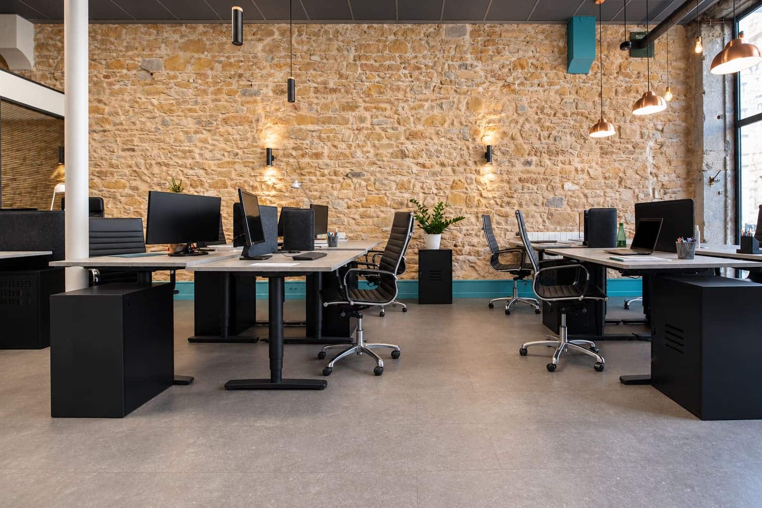 Postes de travail devant le mur en pierre chez 18 Coworking à Lyon 3
